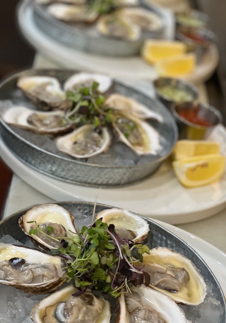 Oysters on a plate with lemon wedges and garnishes.